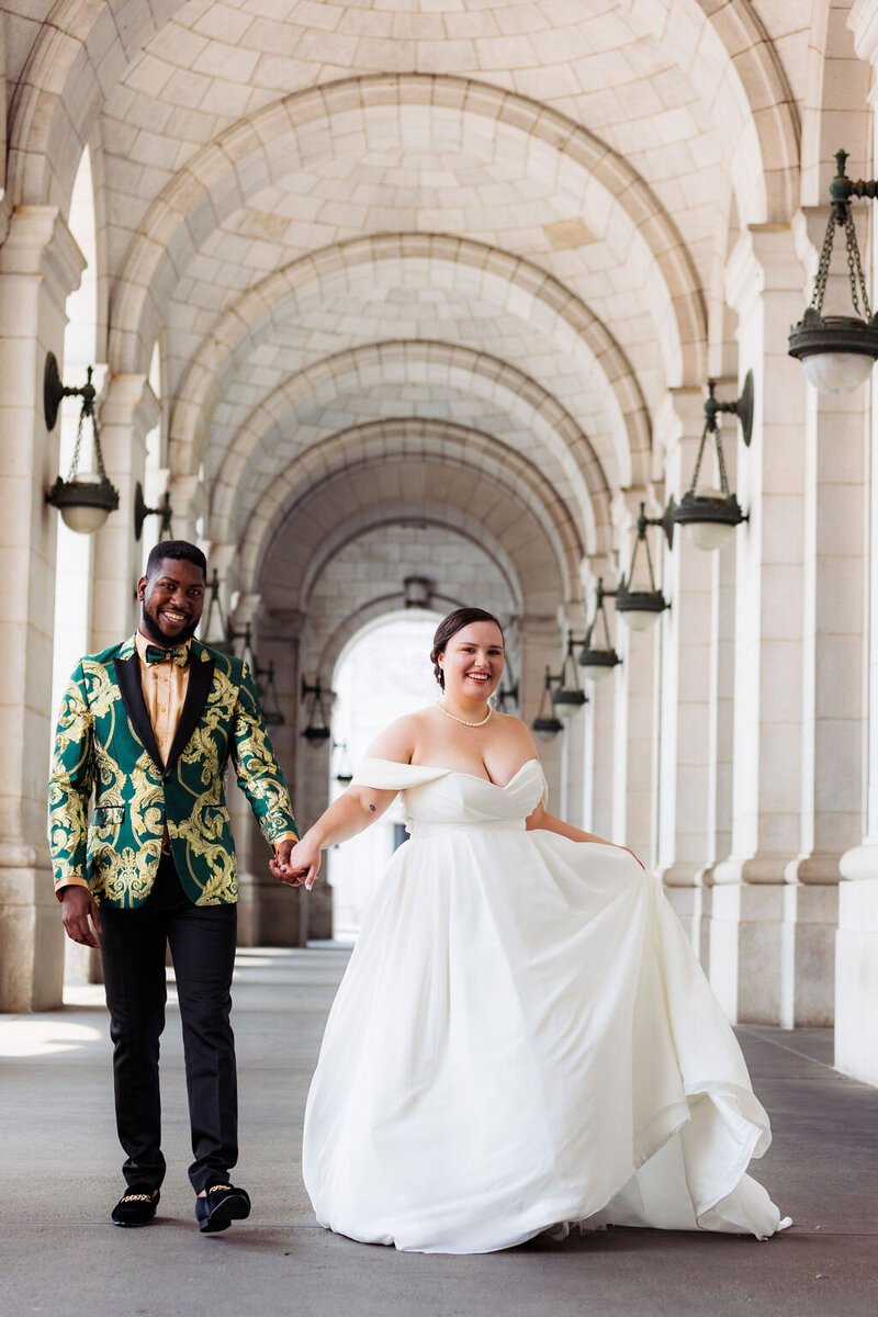 A bride and groom walk through Union Station in DC holding hands after just getting married