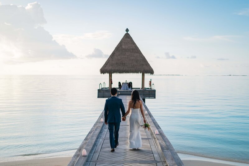 Couple walking down dock in French Polynesia during destination wedding