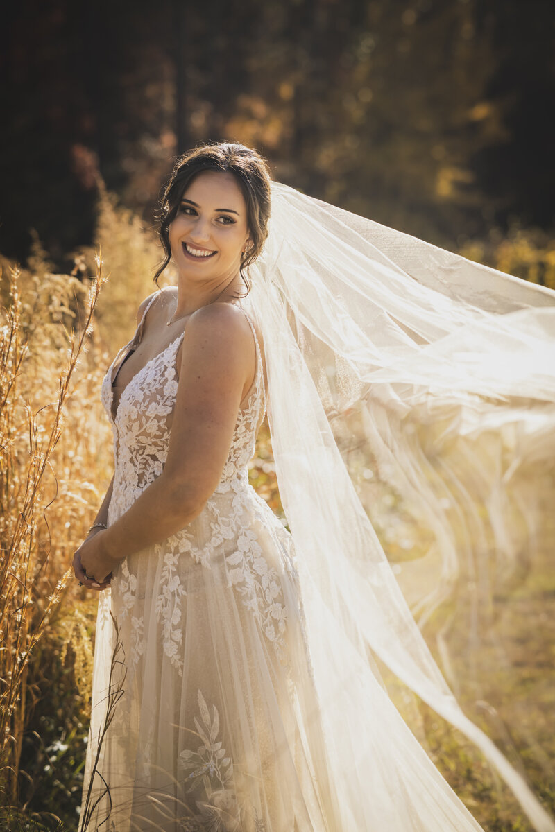 Bride looking over shoulder in a field.