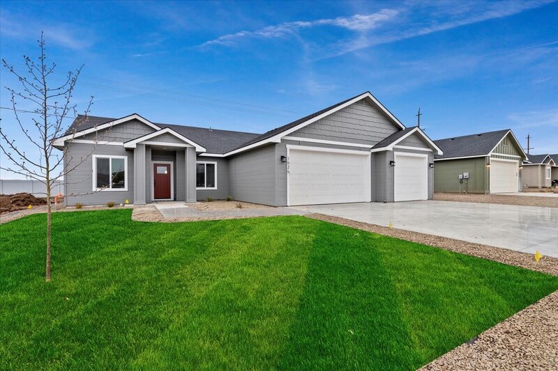 new gray house with red door white garage doors surrounded by trees