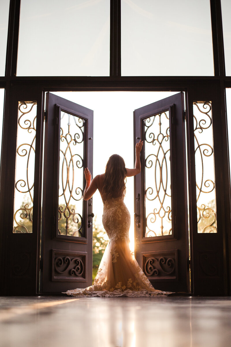 bride standing in door wearing wedding dress at sunset