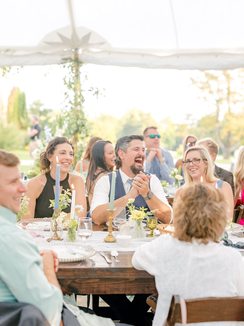 Wedding guests sitting at receptions tables and smiling