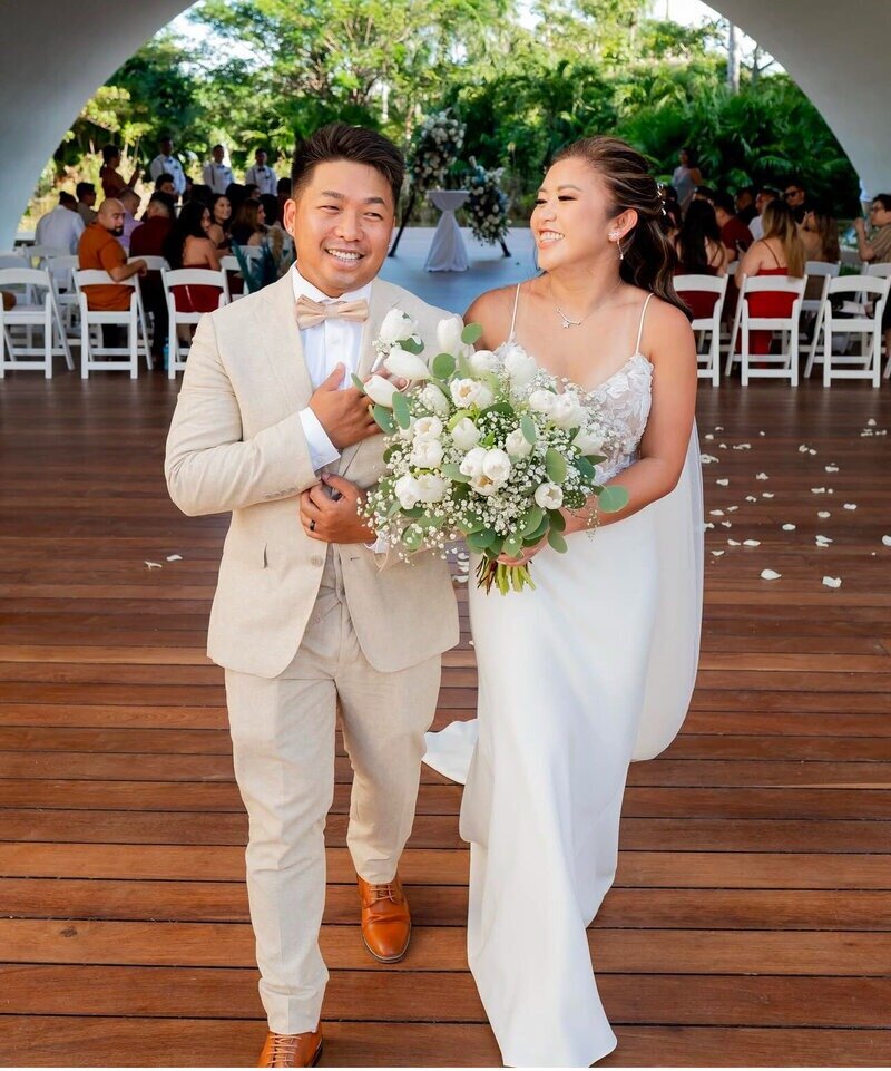 Couple smiling and celebrating after their wedding ceremony, with travel agents for destination weddings