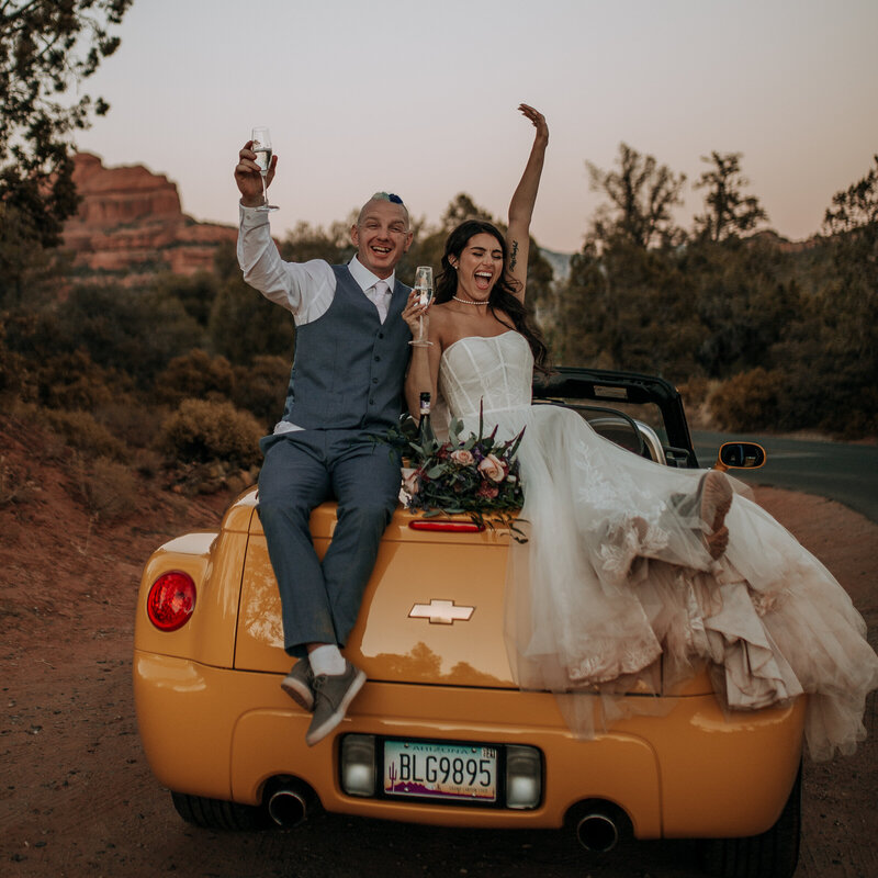 bride and groom sitting on their yellow getaway convertible car
