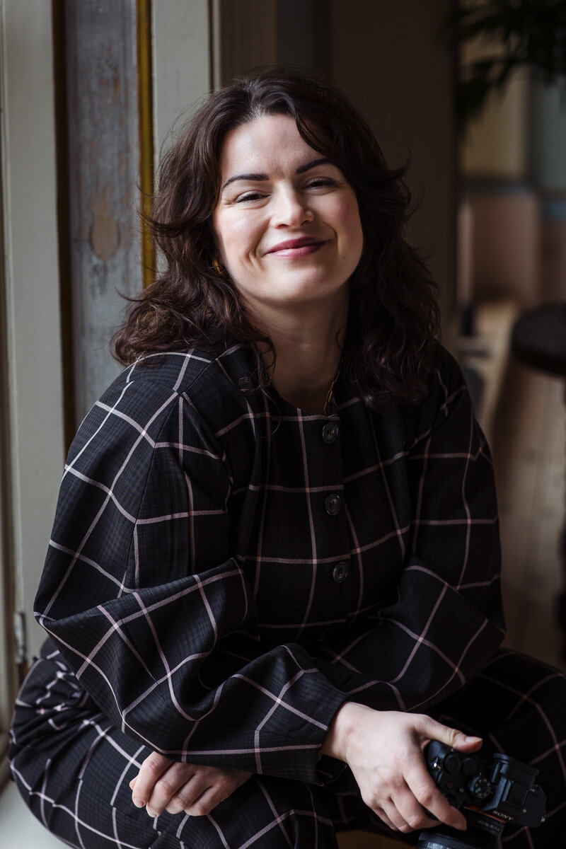 Laura May, UK wedding photographer, smiling in natural light, capturing timeless, vibrant, and artistic wedding photography for sentimental couples across the UK.