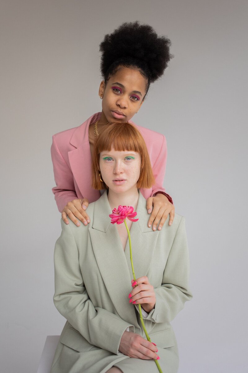 two women in colorful suits holding onto each other and  holding a pink flower