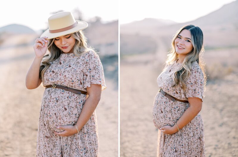 A mom in a neutral floral print dress looks down at her pregnant belly in the golden afternoon sunlight