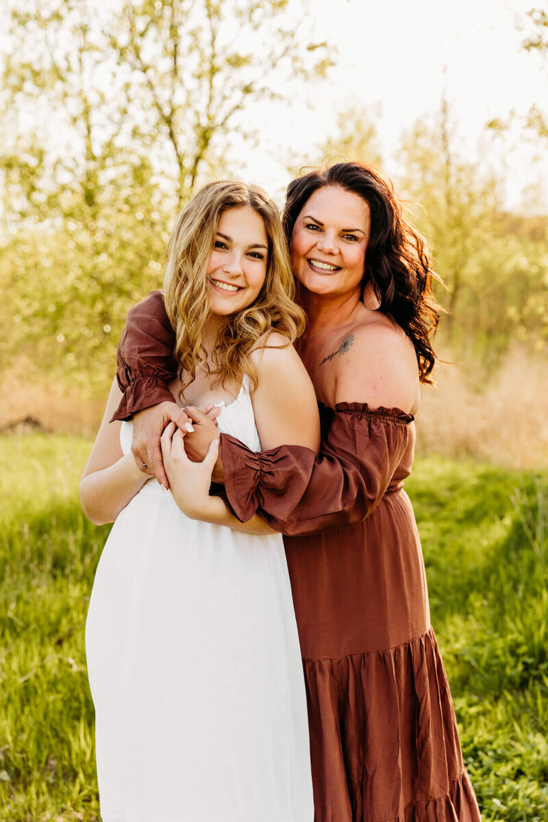 photo of a mom with her arms wrapped around her teen daughter in a field in Door County