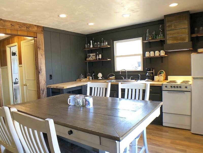 dark rustic kitchen with a large kitchen table and chairs in the middle