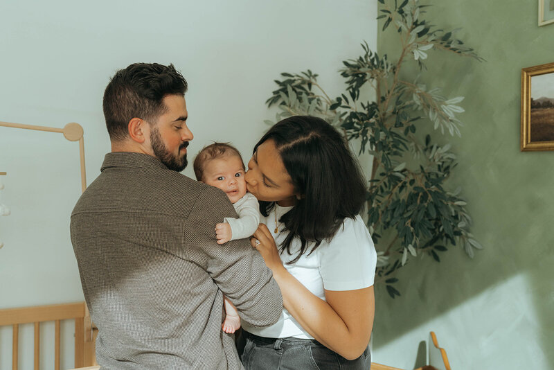 dad holding baby and mom kissing baby's cheek during NYC newborn photoshoot by Elsie Goodman Photography 