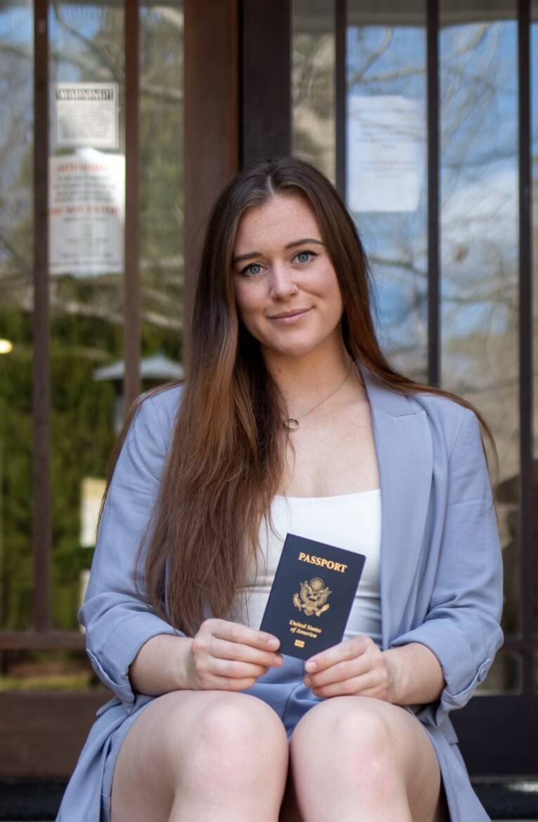 woman in a blue blazer holding a passport