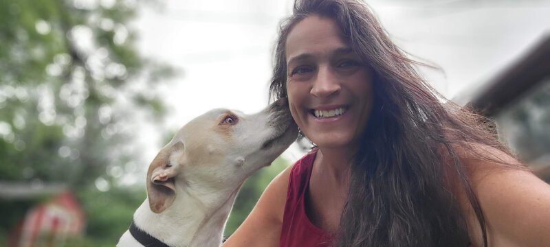 A dog touching their nose to a smiling Karens cheek