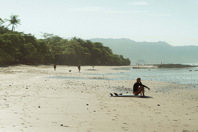 Girl sitting on surfboard on the beach