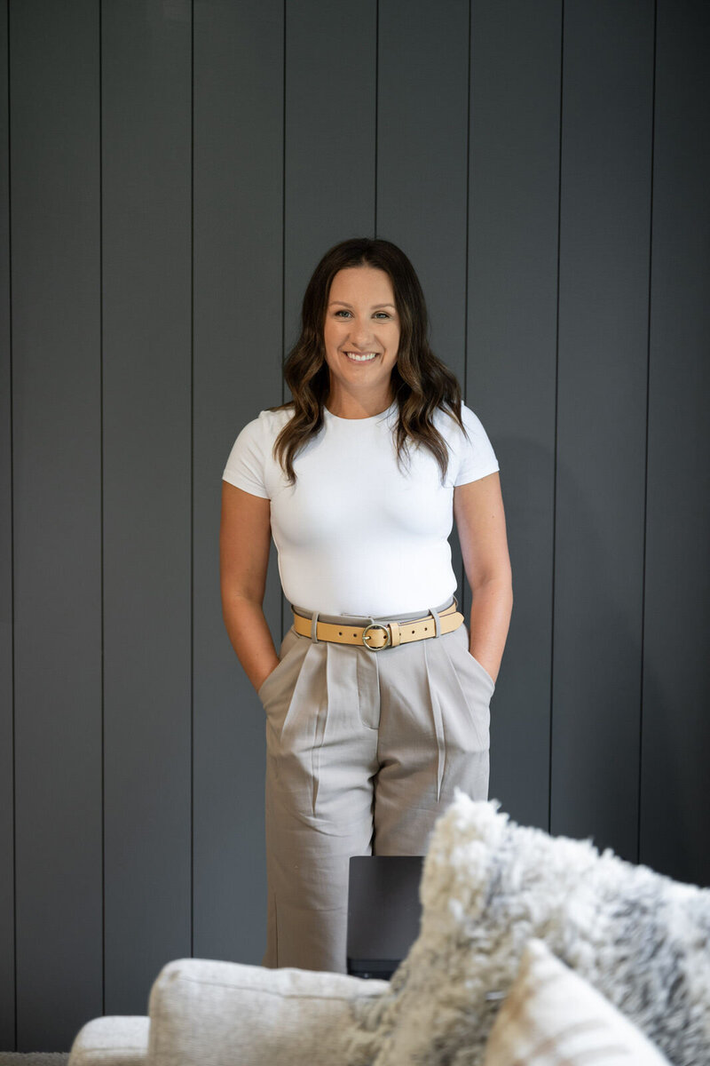 Abby Lucas standing and smiling in front of a dark gray shiplap wall