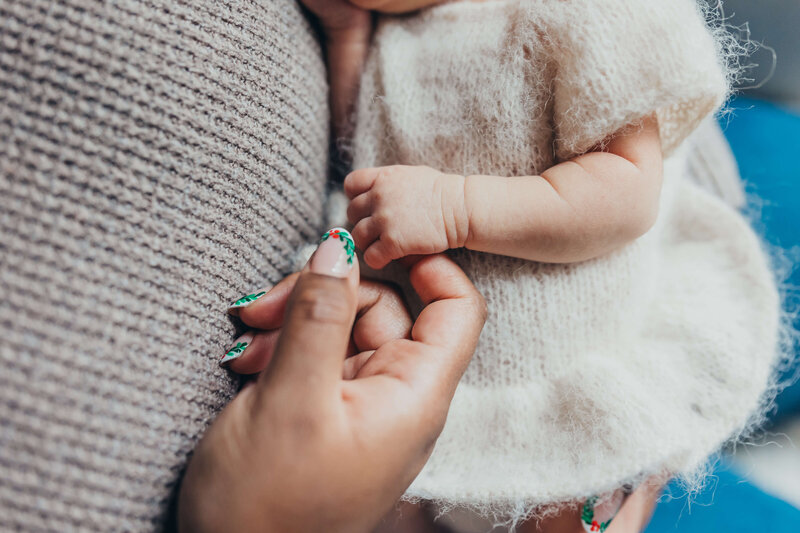 newborn baby girl wrapped in a soft peach wrap with her toes poking out and a tiny pink bow on a newborn bed during newborn session in harrisburg pa