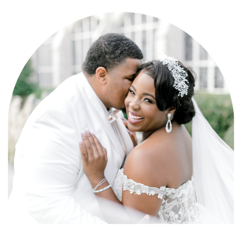African American couple snuggling and laughing together under wedding veil.
