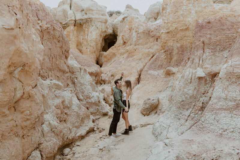 Couple dancing with the pink and orange rocks in the background during their engagement session at Paint Mines in Colorado.