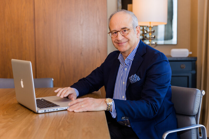Ahmet Bozer wearing a formal outfit sitting at a desk, working on his computer, smiling at the camera during his Atlanta Buckhead branding session
