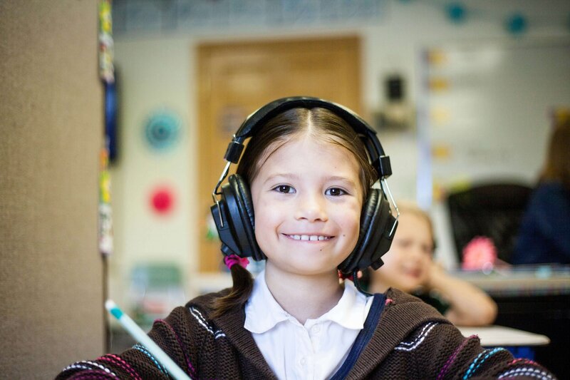 An image of a school aged girl with brown hair wearing headphones waiting for her speech therapy session in Clinton, NJ.