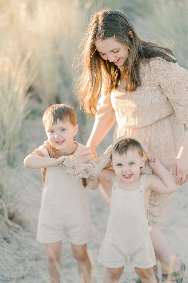 Young boys playing peek-a-boo with moms dress