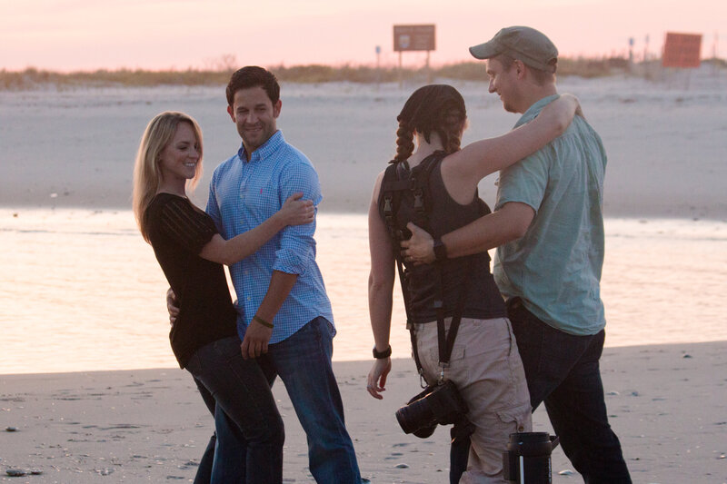 Jen and Travis Stitt demonstrating a romantic dip pose on the beach for an engaged couple during an engagement session, showcasing their teamwork and creativity in crafting stunning and memorable oceanfront photos.