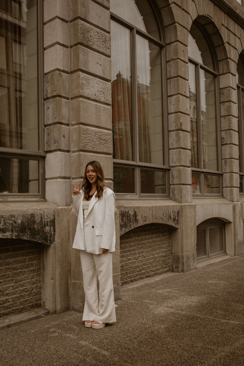 a professional businesswoman dressed in white smiling and posing in front of a big building
