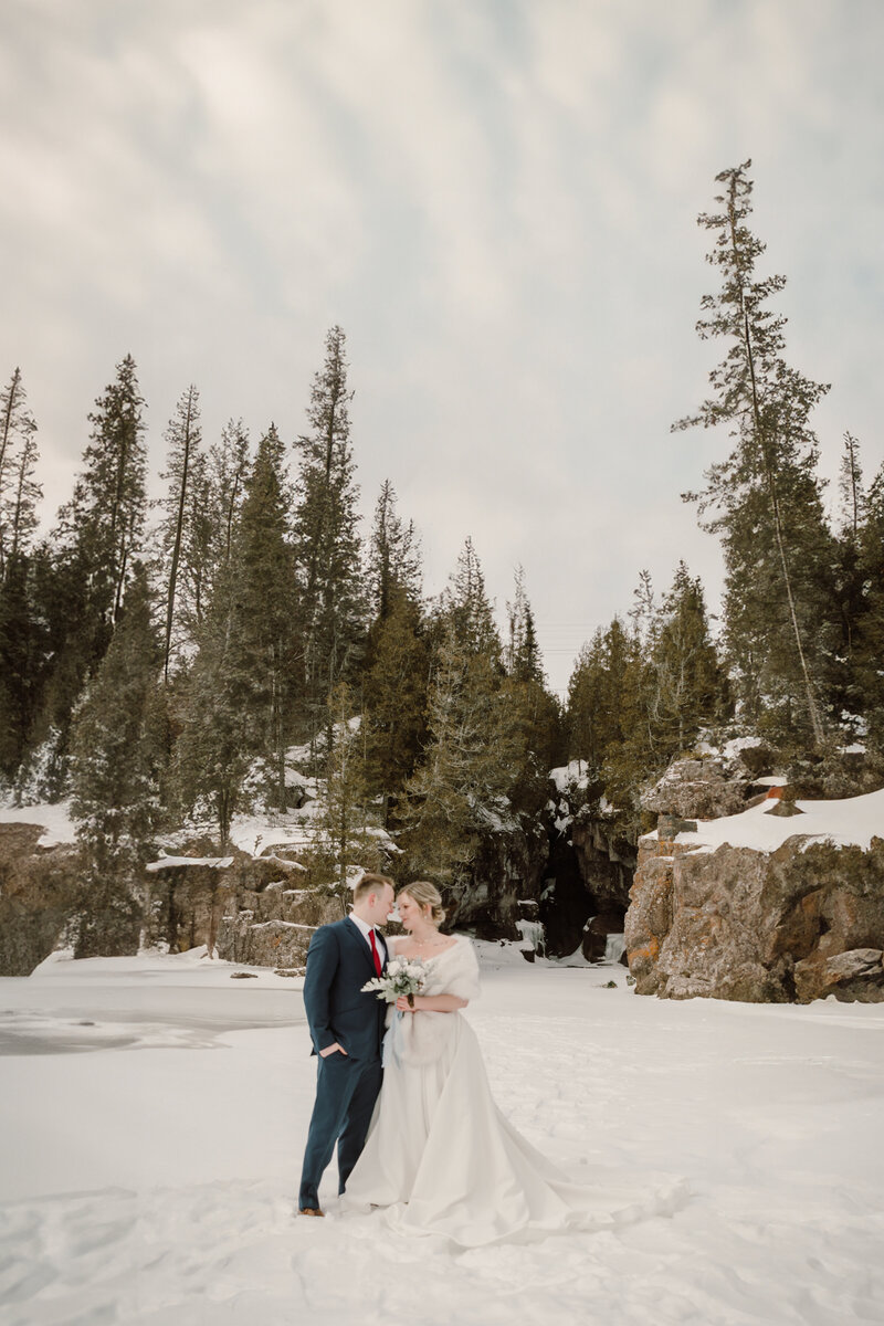 couple stand in snow and smiling