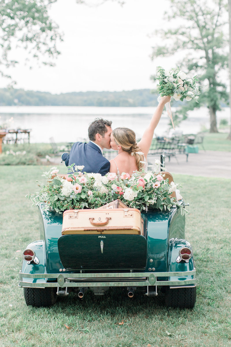 Wedding couple kiss on a car shot from behind