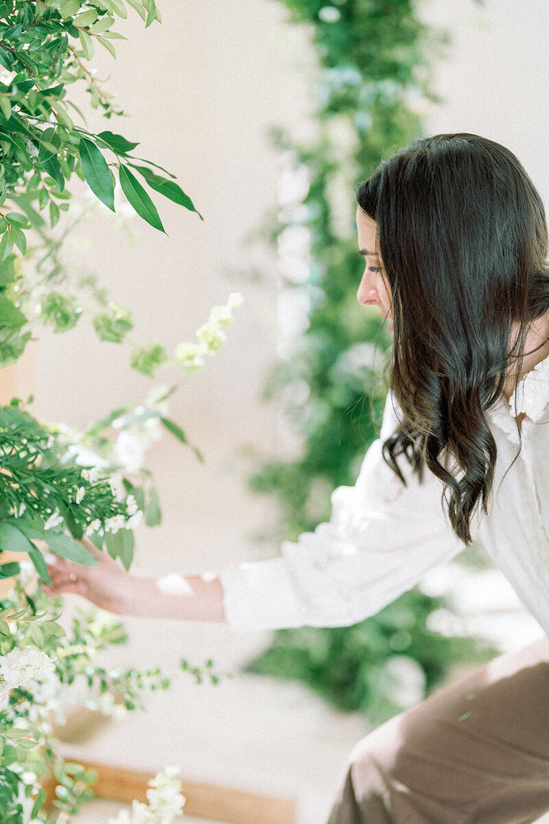 Gracen from Everwild Florals adjusting custom floral arrangements at a hill country wedding