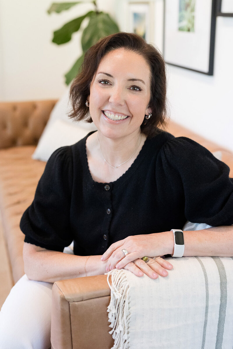 Life coach Dinah McBridge sitting on a couch smiling