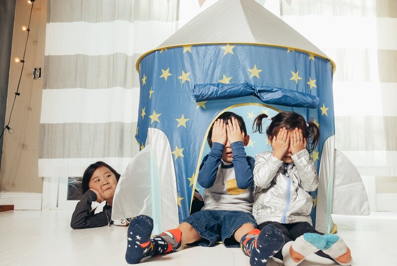 kids covering their eyes in front of play tent