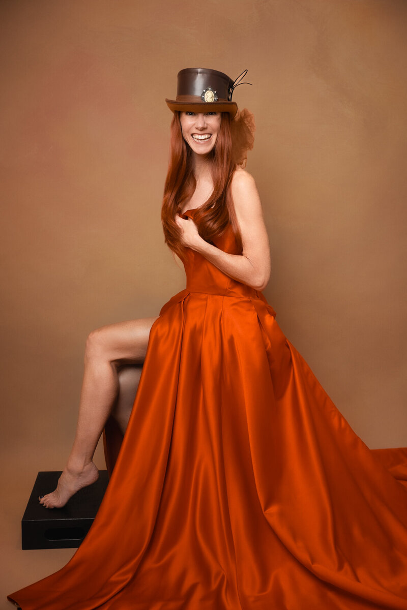 Woman with long hair smiling to the camera covering her nude breast with one arm
