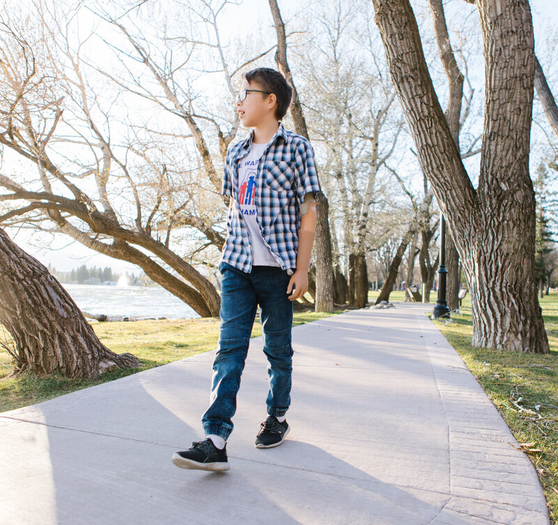 A young boy walking in the park with custom prosthetics, enjoying his mobility.