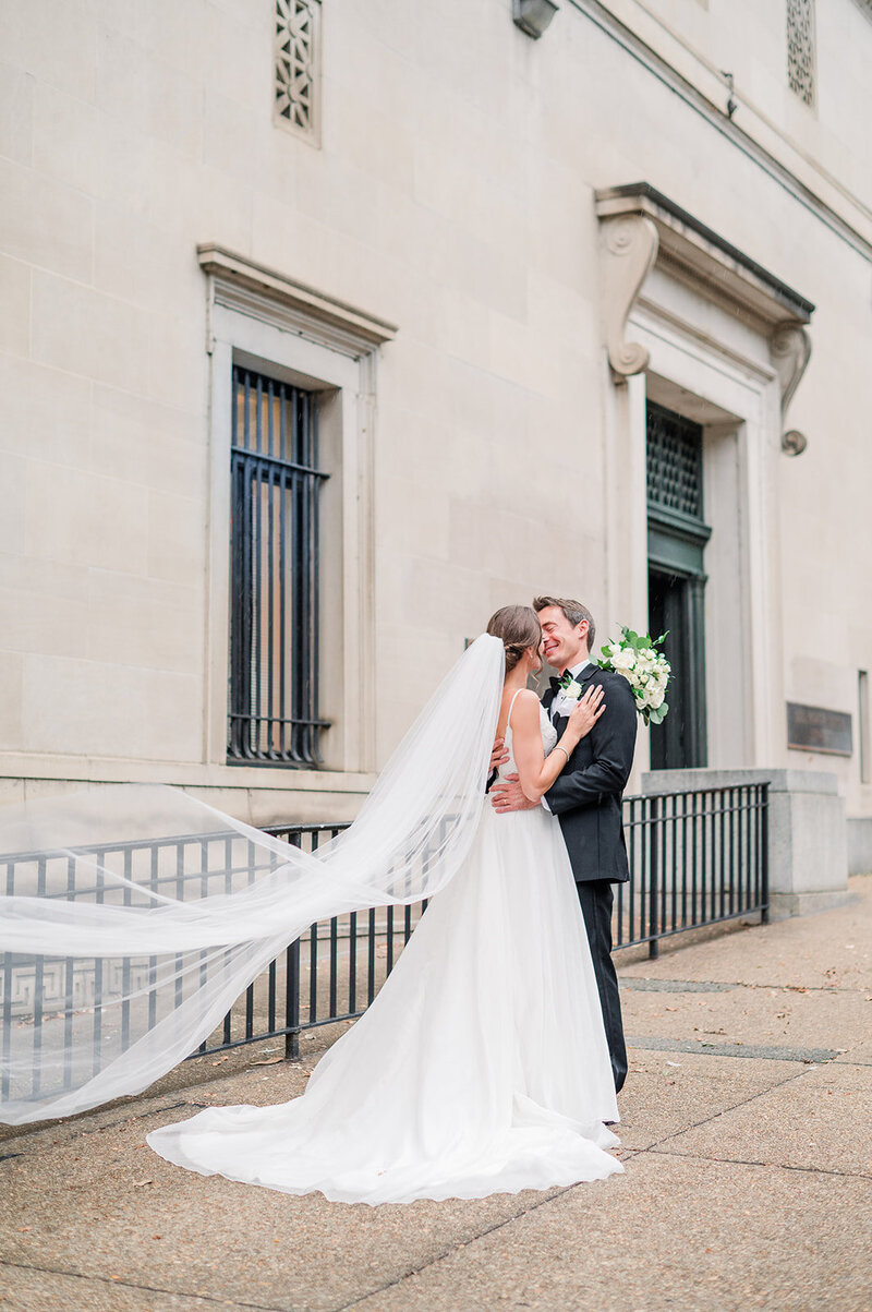 bride and groom kissing outside of a building