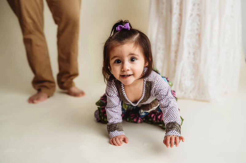 Baby crawls toward the camera during her first birthday photoshoot in Asheville, NC.