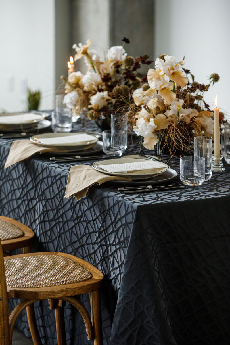 Modern black, cream, and tan place settings at a party dinner table