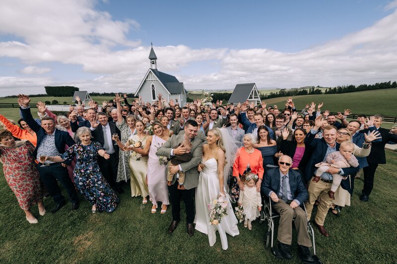 group shot of wedding guests outside the old church at the farm chapel waimumu