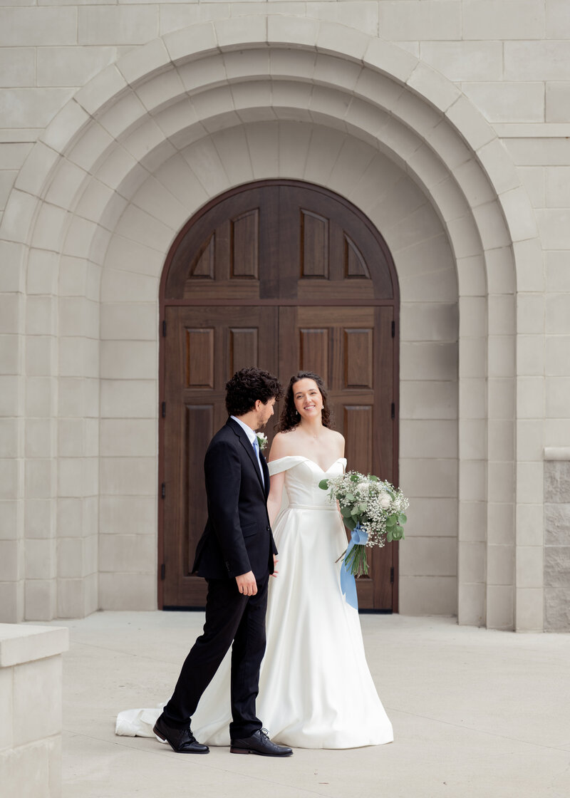 an alabama catholic bride and groom pose in front of elegant doors of the church where they got married in Huntsville, aL