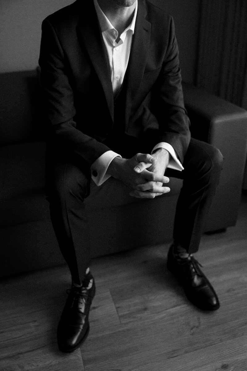 A groom in his suit, patiently waiting in the suite before heading to the ceremony. Girasole & Co. Weddings, a top wedding planner in Columbus, Ohio, specializes in creating personalized, stylish weddings that perfectly reflect your vision. From expert planning to seamless execution, let us help you create a memorable wedding day with attention to every detail.