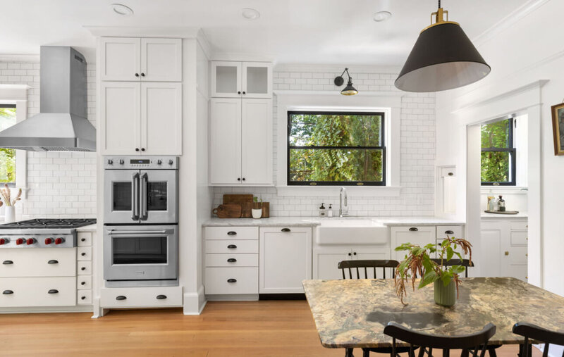 A modern kitchen featuring white cabinets and a built in stove, representing a home option for moving to portland oregon.