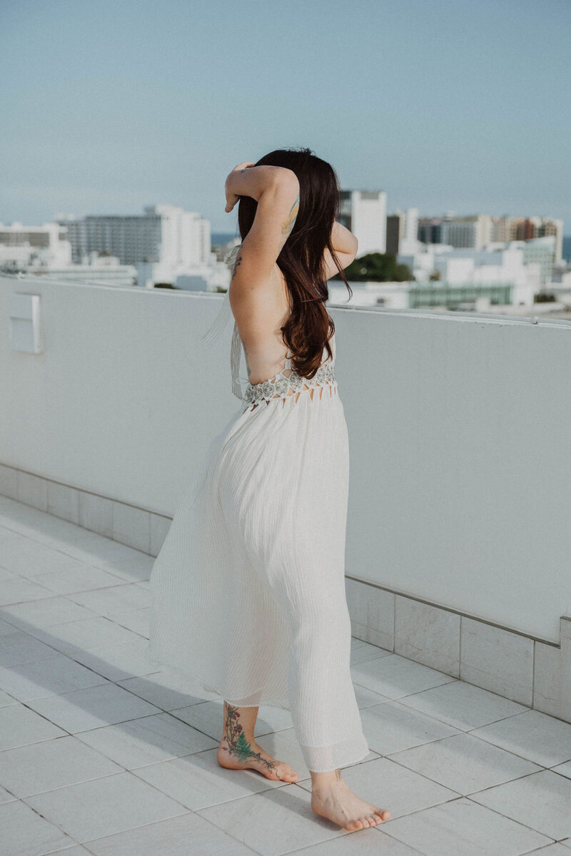Woman in a white dress looking out over the skyline of the city