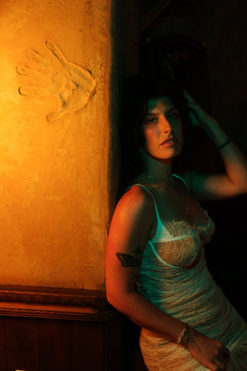 Empowered portrait of Tristan Thibodeau beside a handprint wall—representing founders ready to leave a legacy through intentional, soul-aligned branding.