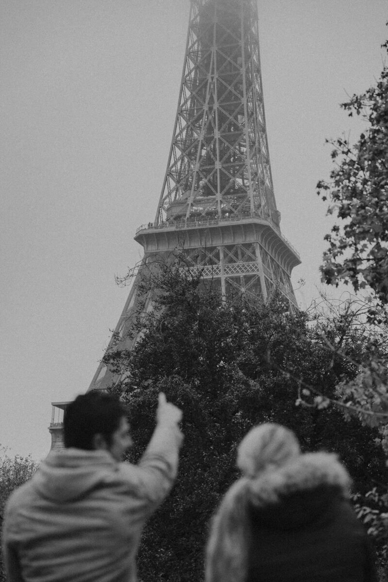 black and white image couple pointing at Eiffel Tower
