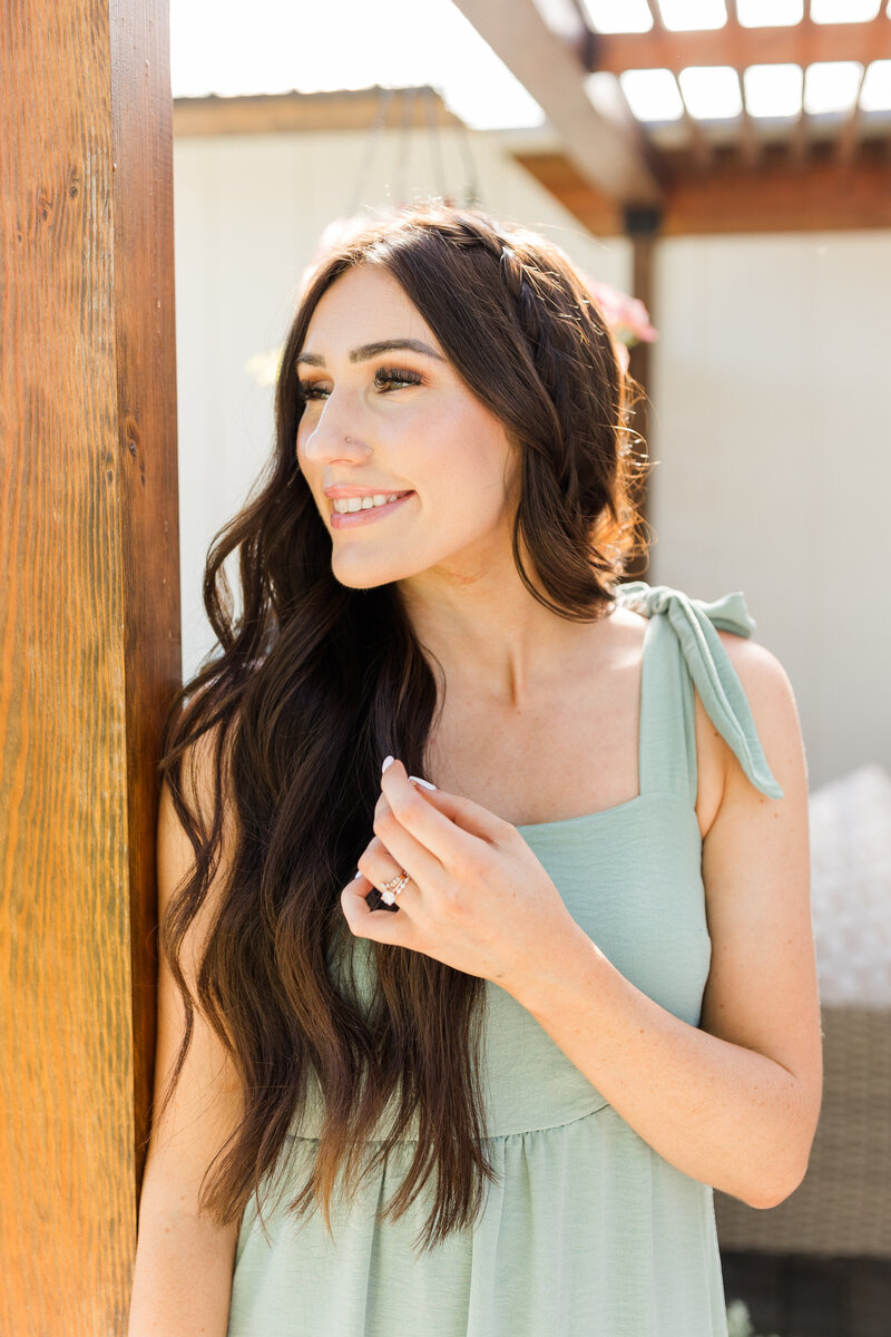 Kali, a wedding and senior photographer in Lewiston, Idaho, smiling in a sunlit outdoor setting.
