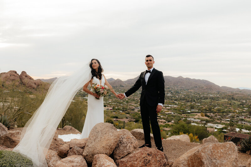 Bride and groom hold hands while looking at the arizona wedding photographer