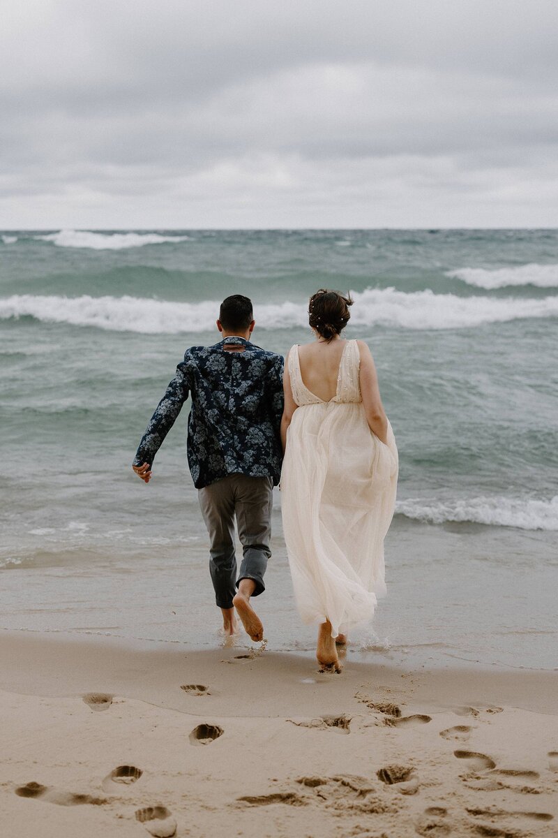a couple running towards the water on the beach on their elopement day