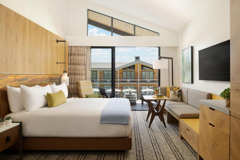 An outdoor wedding ceremony setup featuring wooden chairs and a floral arch on a green lawn.