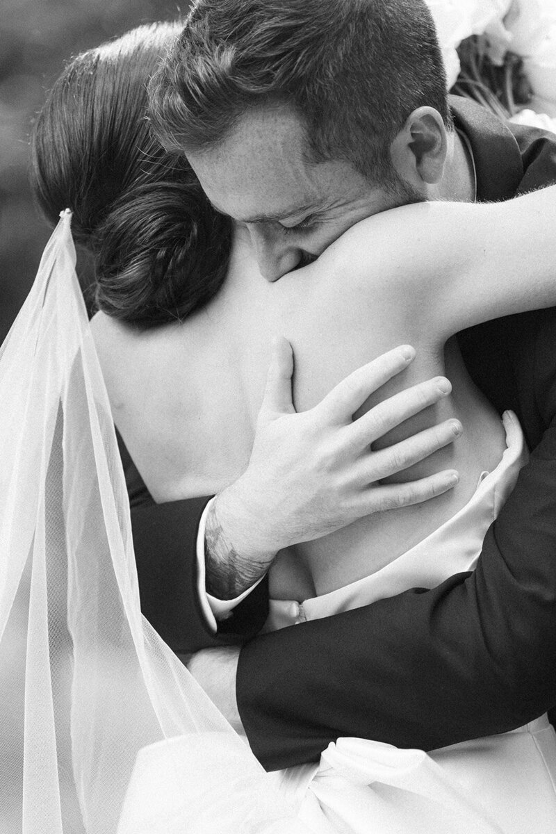 a black and white image of a bride and groom embracing each other in an intimate hug