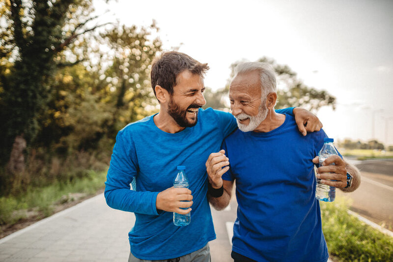 2 men in blue t shirts finishing a run drinking water