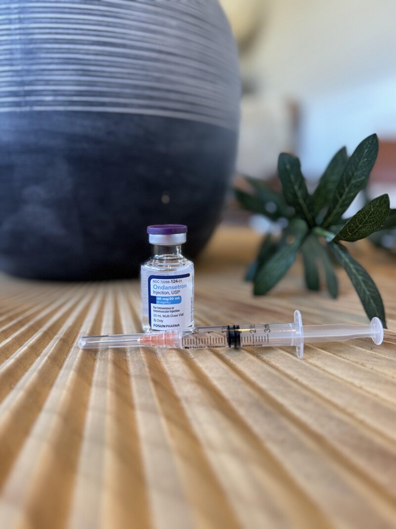 Clear vial filled with clear liquid next to a needle